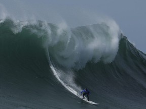 In this Friday, Feb. 12, 2016 file photo Travis Payne rides a giant wave during the finals of the Mavericks surfing contest in Half Moon Bay, Calif.