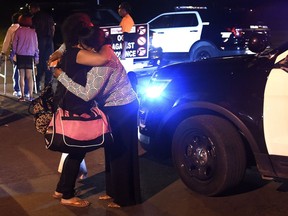 In this Thursday Sept. 20, 2018, photo women hug at the scene where several people were shot, including a child, during a memorial service outside a home in Syracuse, N.Y.