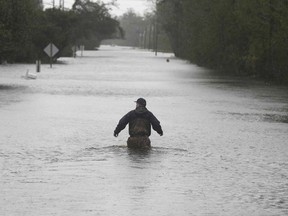A member of the U.S. Coast Guard walks down Mill Creek Road checking houses after tropical storm Florence hit Newport N.C., Saturday, Sept. 15, 2018.