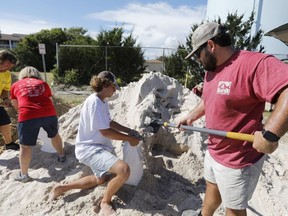 Walker Townsend, at right, from the Isle of Palms, S.C., fills a sand bag while Dalton Trout, in center, holds the bag at the Isle of Palms municipal lot where the city was giving away free sand in preparation for Hurricane Florence at the Isle of Palms S.C., Monday, Sept. 10, 2018.