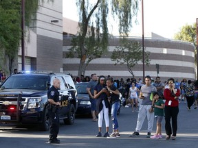 Students and parents wait outside Canyon Springs High School in North Las Vegas after a fatal shooting near a school ball field Tuesday, Sept. 11, 2018.