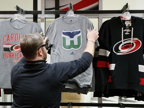 Kurt Cusac, a worker at The Eye store, straightens out Hartford Whalers T-shirts before the doors opened at PNC Arena in Raleigh, N.C., Feb. 1, 2018.  (Chris Seward/The News & Observer via AP)
