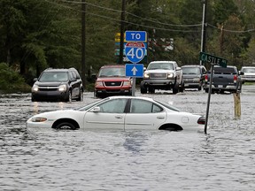 Cars try to navigate a flooded road leading to Interstate 40 in Castle Hayne, N.C., after damage from Hurricane Florence cut off access to Wilmington, N.C., Sunday, Sept. 16, 2018.
