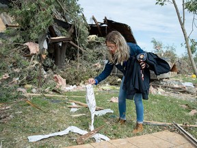 Laurel Wingrove picks up stickers and a firefighter's jacket belonging to her boyfriend that were thrown outside their home when it was damaged by a tornado in Dunrobin, Ont., west of Ottawa, on Sunday, Sept. 23, 2018.