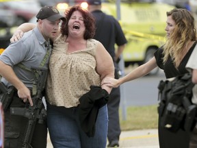 A woman is escorted from the scene of a shooting at a software company in Middleton, Wis., Wednesday, Sept. 19, 2018.
