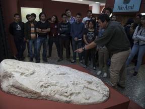 Visitors look at a nearly 1,500-year-old carved altar from the Maya site "La Corona," located in the northern Guatemalan department of Peten, at the National Museum of Archaeology and Ethnology in Guatemala City, Wednesday, Sept. 12, 2018.