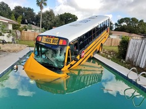 This photo released by the Orange County Sheriff's Office shows a Florida school bus that plowed through a fence and into a backyard pool after a collision, but no one on board was hurt. (Orange County Sheriff's Office via AP)