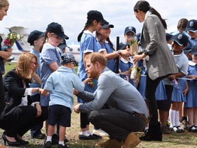 Prince Harry, centre, has his beard tickled by Buninyong Public School student Luke Vincent as his wife Meghan, the Duchess of Sussex greets fellow students following their arrival at Dubbo Regional Airport in Dubbo on October 17, 2018. (DEAN LEWINS/AFP/Getty Images)