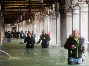 Tourists under arches next to the flooded St Mark's Square during a high-water (Acqua Alta) alert in Venice on Oct. 29, 2018.