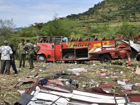 Kenyan police and other rescuers attend the scene of a bus crash near Kericho in western Kenya Wednesday, Oct. 10, 2018. An official says at least 50 people have died after the bus they were traveling in left the road, rolled down a slope and crashed near the western Kenyan town of Kericho.