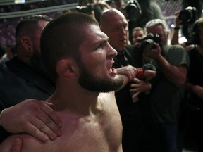 Khabib Nurmagomedov is held back outside of the cage after beating Conor McGregor in a lightweight title mixed martial arts bout at UFC 229 in Las Vegas, Saturday, Oct. 6, 2018. Nurmagomedov won the fight by submission during the fourth round to retain the title.