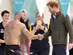 FILE - In this June 8, 2017, file photo, Britain's Prince Harry, right, shakes hands with Australian army veteran Tyronne Gawthorne during a demonstration at the the Aquatic Centre in Sydney. Gawthorne who was featured in promotions for the Invictus Games has withdrawn from the event on Wednesday, Oct. 24, 2018, while facing drugs and weapons charges.