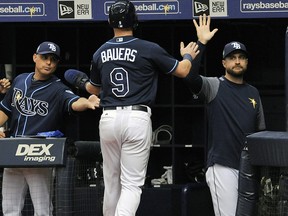 In this June 30, 2018, file photo, Tampa Bay Rays manager Kevin Cash, left, and coach Rocco Baldelli, right, congratulate Jake Bauers (9) during a game in St. Petersburg, Fla. (AP Photo/Steve Nesius, File)