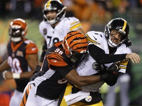 Steelers quarterback Ben Roethlisberger (right) takes a hit from Bengals defensive end Carlos Dunlap (96) during NFL action in Cincinnati, Dec. 4, 2017.