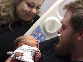 In this Tuesday, Oct. 23, 2018, photo Andrew Goette and his wife, Ashley, look at their baby, Lennon, at United Hospital in Saint Paul, Minn. (Jiwon Choi/Minnesota Public Radio via AP)