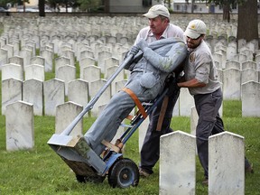 In this Aug. 22, 2017, photo, Bert Cambron, left, and Mark Wilson, employees of Dayton National Cemetery, move the vandalized Civil War Confederate soldier statue that stood in Camp Chase Confederate Cemetery in Columbus, Ohio. (Eric Albrecht/The Columbus Dispatch via AP)