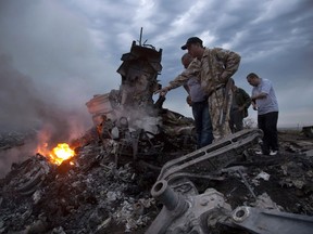 In this Thursday, July 17, 2014 file photo, people inspect the crash site of a passenger plane near the village of Grabovo, Ukraine.