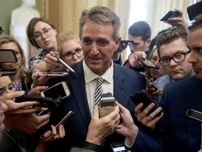 In this Sept. 28, 2018 photo, Sen. Jeff Flake, R-Ariz., centre, speaks with reporters after meeting with Senate Majority Leader Mitch McConnell of Ky. in his office in the Capitol in Washington.
