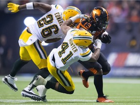 Edmonton Eskimos defensive back Chris Edwards and Edmonton Eskimos defensive back Monshadrik Hunter  try to take down BC Lions running back Tyrell Sutton  during CFL  action in Vancouver, on Friday, Oct. 19, 2018.