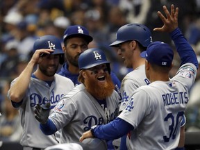Los Angeles Dodgers' Justin Turner celebrates with manager Dave Roberts (30) after hitting a two-run home run during the eighth inning of Game 2 of the National League Championship Series baseball game against the Milwaukee Brewers Saturday, Oct. 13, 2018, in Milwaukee. (AP Photo/Jeff Roberson)