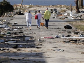 People hold hands as they walk amidst destruction in the aftermath of Hurricane Michael in Mexico Beach, Fla., Thursday, Oct. 11, 2018.