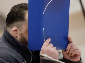 The defendant covers his face with a folder as he arrives at the temporay Oldenburg district court at the Weser Ems halls in Oldenburg, Germany, Tuesday, Oct. 30, 2018.