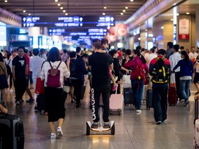 A man rides on a segway with a small girl at the Hongqiao train station in Shanghai on October 1, 2016. China celebrates 'Golden Week' on October 1 with a week-long holiday to commemorate the founding of the Peoples Republic of China. / AFP / JOHANNES EISELE (Photo credit should read JOHANNES EISELE/AFP/Getty Images)