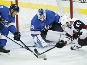 Arizona Coyotes’ Jason Demers can’t get his stick on the puck as Jets goalie Laurent Brossoit and defenceman Andrew Copp close in during Saturday's game in Winnipeg. Brossoit finished with 42 saves. (JOHN WOODS/THE CANADIAN PRESS)