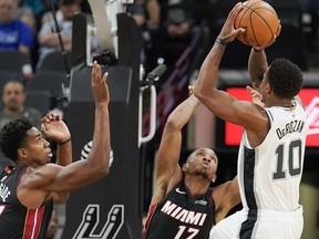 San Antonio Spurs' DeMar DeRozan (10) shoots against Miami Heat's Hassan Whiteside (21) and Rodney McGruder during the first half of an NBA preseason basketball game, Sunday, Sept. 30, 2018, in San Antonio.