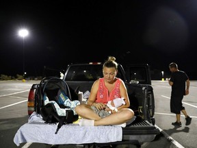 In this Monday, Oct. 15, 2018 file photo, Lorrainda Smith sits with her 2-day-old son, Luke, as she contemplates with her husband, Wilmer Capps, right, sleeping in their truck in a parking lot in Panama City, Fla. .