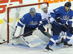 Toronto Maple Leafs centre John Tavares (centre) cuts between Winnipeg Jets goaltender Connor Hellebuyck and defenceman Igor Kulikov in Winnipeg on Wed., Oct. 24, 2018. Kevin King/Winnipeg Sun/Postmedia Network