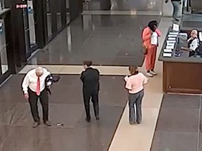 In this July 3, 2018, file photo from a surveillance video provided by the Cook County Sheriff's Office, Cook County Circuit Judge Joseph Claps, left, looks down at an object he allegedly dropped in the lobby of the Leighton Criminal Court Building in Chicago. (Cook County Sheriff's Office via AP, File)