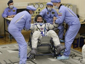 Russian Space Agency experts help Russian cosmonaut Alexey Ovchinin, a member of the main crew of the expedition to the International Space Station (ISS), to stand up after inspecting his space suit prior to the launch of Soyuz MS-10 space ship at the Russian leased Baikonur cosmodrome, Kazakhstan, Thursday, Oct. 11, 2018.