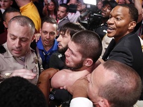 Khabib Nurmagomedov, bottom centre, is held back outside the cage after fighting Conor McGregor at UFC 229 in Las Vegas, Saturday, Oct. 6, 2018. (AP Photo/John Locher)