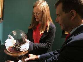 Lori Page and gallery owner Bill Rau of M.S. Rau Antiques prepare to remove the glass dome from a pedestal holding a set of small binoculars, or opera glasses, believed to have been held by President Abraham Lincoln on the night he was assassinated at Ford's Theatre in 1865, Thursday, Sept. 27, 2018 in New Orleans. (AP Photo/Kevin McGill)