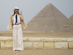 First lady Melania Trump reaches for her hat as she pauses for media during a visit to the historical Giza Pyramids site near Cairo, Egypt on Saturday, Oct. 6, 2018. Trump is visiting Africa on her first big solo international trip.