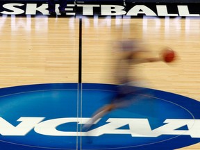 In this March 14, 2012, file photo, a player runs across the NCAA logo during practice in Pittsburgh before an NCAA tournament college basketball game.
