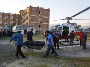 Officials unload the bodies after a helicopter carrying bodies of those killed in Gurja Himal mountain arrives at the Teaching hospital in Kathmandu, Nepal, Sunday, Oct. 14, 2018.