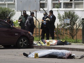 Two bodies, one identified as prison guard Juan Sical Toj, lie covered outside the Roosevelt Hospital after an assault staged by unknown attackers, in Guatemala City, Wednesday, Aug. 16, 2017. (AP Photo/Luis Soto)