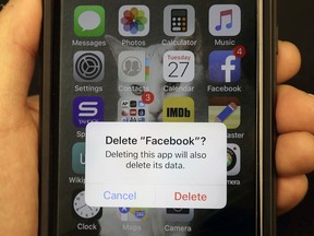 In this March 27, 2018, file photo, a reporter holds a phone showing the Facebook app in San Francisco.
