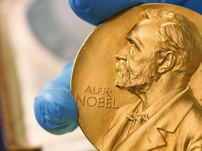 FILE- In this April 17, 2015, file photo a national library employee shows the gold Nobel Prize medal awarded to the late novelist Gabriel Garcia Marquez, in Bogota, Colombia. This year's round of Nobel Prizes begins Monday, Oct. 1, 2018, with the award for medicine or physiology, honoring research into the microscopic mechanisms of life and ways to fend off the invaders who cut it short.