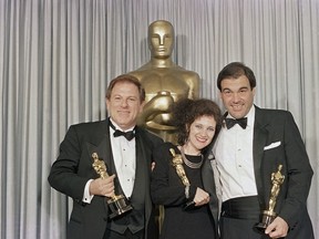 In this Monday, March 31, 1987 file photo, Claire Simpson, center, is flanked by Arnold Kopelson, left, and Oliver Stone as the threesome meets backstage at the Dorothy Chandler Pavilion in Los Angeles after receiving Oscars, for best editing (Simpson), best direction (Stone) and best picture (Kopelson) for the film, "Platoon." Kopelson, a versatile film producer whose credits ranged from the raunchy teen smash "Porky's" to the Holocaust drama "Triumph of the Spirit" to the Oscar-winning "Platoon," died Monday, Oct. 8, 2018, at age 83. Family spokesman Jeff Sanderson told The Associated Press that Kopelson died of natural causes at his home in Beverly Hills, Calif.