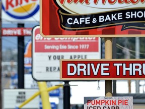 FILE - In this Tuesday, Aug. 26, 2014 file photo, fast food restaurant signs line Peach Street in Erie, Pa. A Centers for Disease Control and Prevention study released on Wednesday, Oct. 3, 2018 finds that one in three U.S. adults eat fast food on any given day.