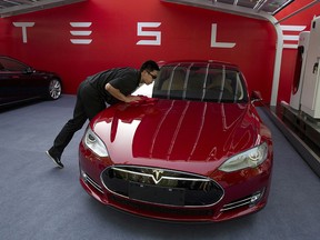 In this April 22, 2014, file photo, a worker cleans a Tesla Model S sedan before an event to deliver the first set of cars to customers in Beijing. (AP Photo/Ng Han Guan, File)