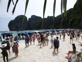 In this photo taken Thursday, May 31, 2018, tourists enjoy the beach on Maya Bay, Phi Phi Leh island in Krabi province, Thailand. Maya Bay will close to tourists indefinitely until its ecosystem returns to its full condition, the Department of National Parks, Wildlife and Plant Conservation said in a Monday announcement published on the Royal Gazette.