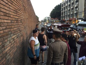 In this Thursday, Oct. 18, 2018, photo, Canadian Brittney Lorretta Katherine Schneider, left, and British Furlong Lee, second left, stand in front of Tha Pae Gate in Chiang Mai province, northern Bangkok, Thailand. They face up to 10 years in prison on charges of spraying paint on an ancient wall in northern Thailand, police said Friday. (Chiang Mai News via AP)