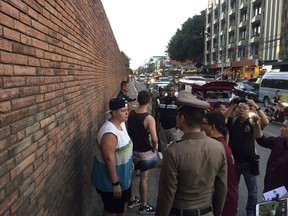 In this Thursday, Oct. 18, 2018, photo, Canadian Brittney Schneider, left, and Briton Furlong Lee, second left, stand in front of Tha Pae Gate in Chiang Mai province, northern Bangkok, Thailand. They face up to 10 years in prison on charges of spraying paint on an ancient wall in northern Thailand, police said.