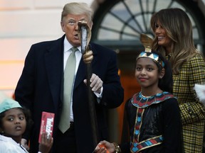 U.S. President Donald Trump holds up part of a child's Halloween costume as he and first lady Melania Trump give candy to children during a Halloween trick-or-treat event at the White House, Sunday, Oct. 28, 2018, in Washington.