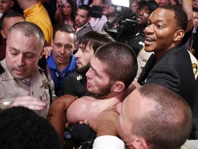 Khabib Nurmagomedov, bottom centre, is held back outside of the cage after fighting Conor McGregor in a lightweight title bout at UFC 229 in Las Vegas, Saturday, Oct. 6, 2018.