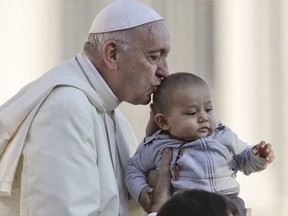 Pope Francis kisses a child as he arrives with the popemobile in St.Peter's Square to held his weekly general audience at the Vatican, Wednesday, Oct. 10, 2018.
